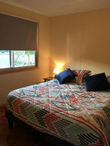 1 dormitorio con 1 cama grande con almohadas azules en Cabana Quillon, en Quillón
