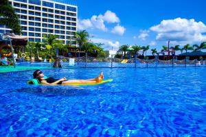 a woman and a dog on a surfboard in the water at Harman Resort Hotel Sanya in Sanya