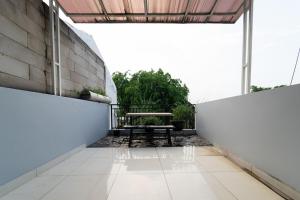 een patio met een bank en een tafel aan een muur bij KoolKost near Ragunan Zoo - Minimum Stay 6 Days in Jakarta