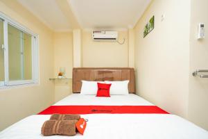 a small room with a bed with a red pillow at RedDoorz Syariah near Exit Toll Ciawi in Bogor