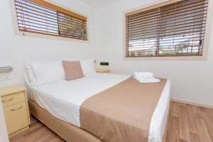 um quarto com uma cama grande e 2 janelas em BIG4 Park Beach Holiday Park em Coffs Harbour