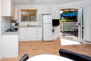 a kitchen with a white refrigerator and a balcony at BIG4 Park Beach Holiday Park in Coffs Harbour