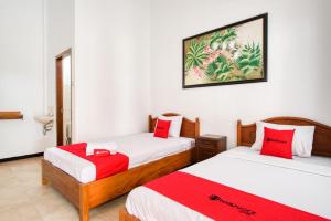 a room with two beds with red and white sheets at RedDoorz Syariah near Gor Ken Arok in Malang