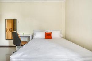 Una cama en una habitación con una almohada naranja. en KoolKost Syariah near Kaza Mall Surabaya, en Surabaya