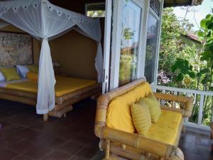 a porch with a couch and an umbrella at Stairway To Heaven Bungalows and Restaurant in Amed