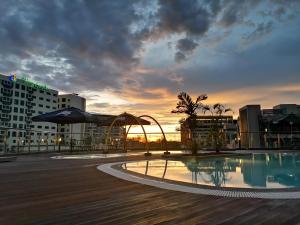 a pool on the roof of a building with a sunset at Sabah Oriental Hotel in Kota Kinabalu