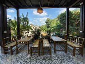 a patio with wooden benches and a large window at Mai Chau Rustic Home in Mai Châu