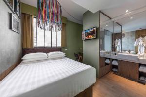 um quarto com uma cama grande e uma casa de banho em Hotel Gin Bugis Singapore - previously Hotel G em Singapura