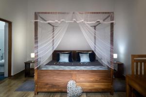 a bedroom with a canopy bed with blue pillows at Madla rooms in Weligama