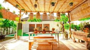 an outdoor patio with a table and benches at Villa Sarong 2 in Seminyak