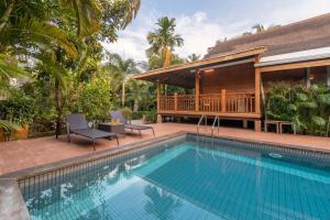 a swimming pool in front of a villa at Nature's Abode - The Wooden Villa at Morjim by StayVista in Morjim