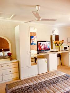 a bedroom with a bed and a desk with a television at Colonial Motor Inn Pambula in Pambula