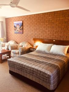 a bedroom with a bed and a brick wall at Colonial Motor Inn Pambula in Pambula