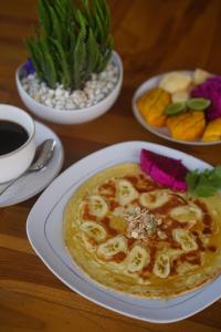 a table with a bowl of soup and plates of fruit at Arjuna Bungalow in Nusa Penida