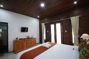 a bedroom with a large bed with a wooden ceiling at Arjuna Bungalow in Nusa Penida