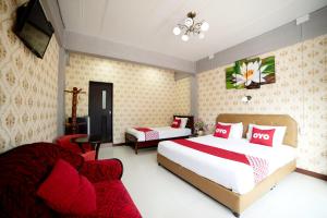 a hotel room with two beds and a chair at OYO 465 Krung Kao Traveller Lodge in Phra Nakhon Si Ayutthaya