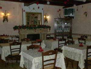 una sala da pranzo con tavoli bianchi e camino di Albergo Andromeda a Pescasseroli