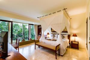 a bedroom with a canopy bed and a balcony at Cepik Villa Sidemen by AGATA in Sidemen