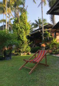 a wooden bench sitting on the grass near a building at ครูหนูบ้านพัก แหลมงอบ Krunou baanpak in Trat