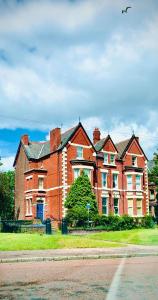 een groot rood bakstenen huis aan de kant van een straat bij Cosy Apartment in Safe Area in Liverpool