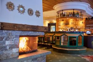 a fireplace in a restaurant with a bar in the background at Hotel Erzberg in Zürs am Arlberg