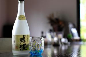 a bottle of wine and a glass on a table at Nangoku Lodge Booya in Onna