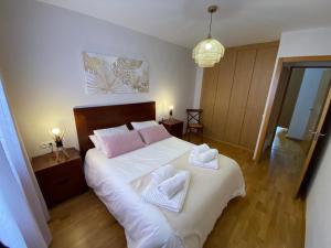 a bedroom with a large bed with two towels on it at Fantástico Apartamento con jardín en Castiello de Jaca in Castiello de Jaca