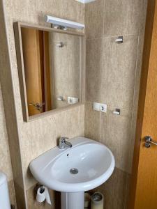 ein Badezimmer mit einem weißen Waschbecken und einem Spiegel in der Unterkunft Fantástico Apartamento con jardín en Castiello de Jaca VUT HU-20-007 in Castiello de Jaca