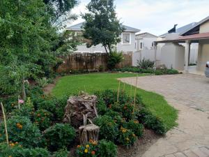 einen Garten mit Blumen in einem Hof mit einem Haus in der Unterkunft LPM Guest in Pretoria