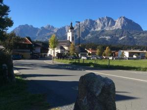 a large rock in front of a church with mountains at APARTMENTS Pension Foidl in Oberndorf in Tirol