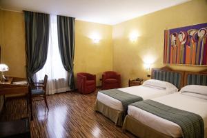 una camera d'albergo con 2 letti e una scrivania di Best Western Hotel Artdeco a Roma
