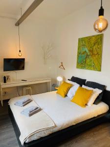 1 dormitorio con cama con almohadas amarillas y escritorio en L’atelier St Remacle, en Lieja