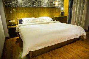 1 dormitorio con 1 cama grande con sábanas y almohadas blancas en VIZ Culture & Arts Apartment en Nanning