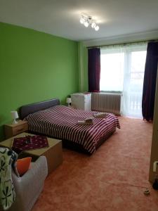 a bedroom with a bed and a couch and a window at Grill Garten Vendégház in Keszthely