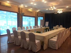 uma grande mesa longa com cadeiras brancas num quarto em ATS Hotel em Hanói