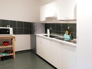 cocina con armarios blancos, fregadero y microondas en City center apartment, en Umag
