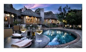 a table with wine glasses next to a swimming pool at Granny Mouse Country House & Spa in Balgowan