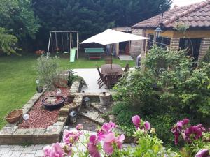 einen Garten mit einem Tisch und einem Regenschirm und ein paar Blumen in der Unterkunft Carpe Diem Bed & Breakfast in Sélestat