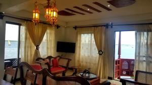 a living room with chairs and a television and windows at Beytul Habaib in Lamu