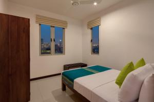 a bedroom with a bed and windows with a city skyline at CASAMIA Colombo @ On Three20 in Colombo