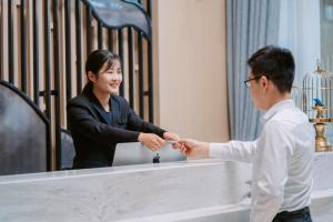 a man and a woman shaking hands over a counter at Atour Hotel Changsha Lugu Branch in Changsha