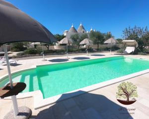 a swimming pool with an umbrella next to a resort at Il Carpino in Martina Franca