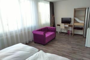 einen lila Stuhl in einem Zimmer mit einem TV in der Unterkunft Atelierhaus Budget Hotel in Filderstadt