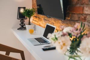 a desk with a laptop computer and flowers on it at Apartamenty Schoeps Residence by Noclegi Renters in Poznań