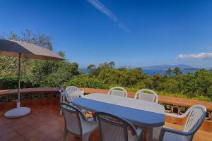 a table and chairs on a patio with an umbrella at Villa PLEIN SOLEIL- Plage d'Argent à 150 m - 150 m from beach in Coti-Chiavari