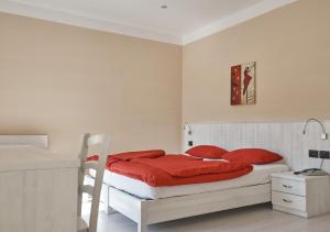 a white bedroom with a bed with red pillows at Hotel du Lac Parc & Residence in Lavarone