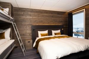 Svalbard Hotell | Lodge في لونغييربين: غرفة نوم بسرير كبير وجدار خشبي