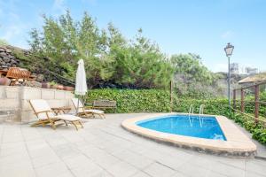 una piscina en un patio con sillas y sombrilla en Viv Vac La Casita del Viejo, en Guía de Isora