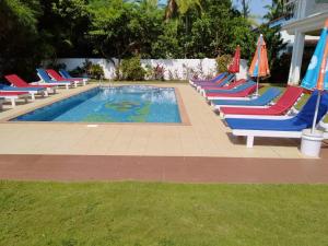 a row of lounge chairs with umbrellas next to a swimming pool at Bluesea Beach Resort in Candolim
