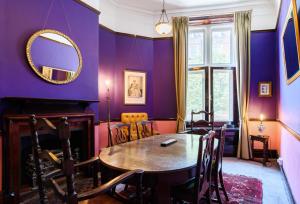 a dining room with purple walls and a table and chairs at City Centre Mansion Sleeping 1 to 23 in Cardiff